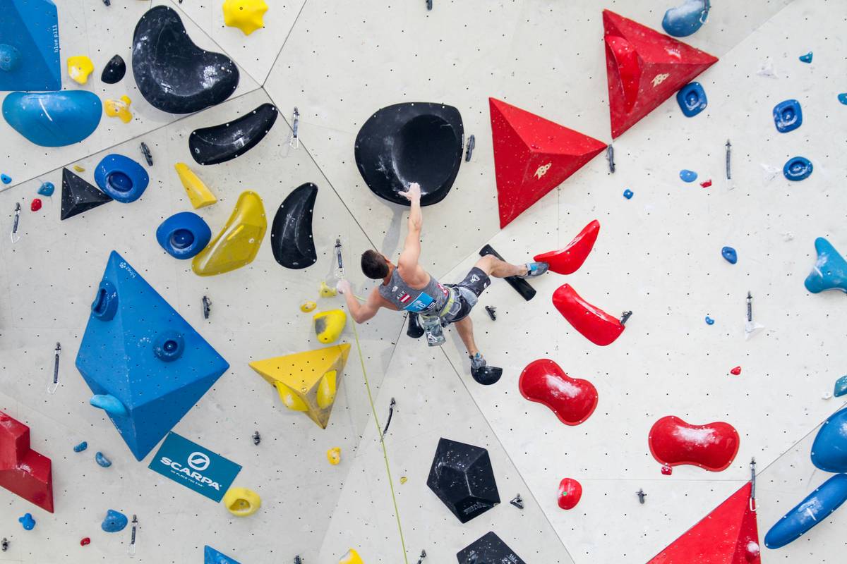 Rock Climbing pro placing a tricam in a flared granite crack